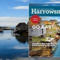 An image of the summer 2021 issue. It features a photo of a fishing village on the East coast of Canada. The houses are multi-coloured and there is a small fishing boat in the ocean nearby. | Harrowsmith Magazine
