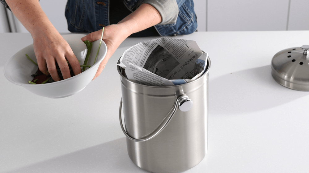 A metal bin composter with newspaper liner.