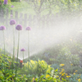 A photograph of a water sprinkler spraying water in a flower garden.
